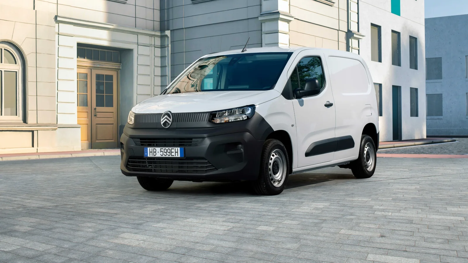 Citroën Berlingo Van First alb, fotografiat din față într-un decor urban, cu caroserie închisă pentru transportul de marfă.