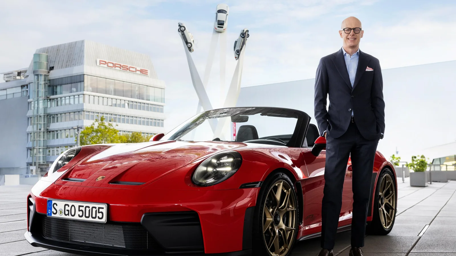 Michael Leiters, președintele Porsche AG, lângă un Porsche 911 Cabriolet roșu, în fața sediului mărcii din Zuffenhausen.