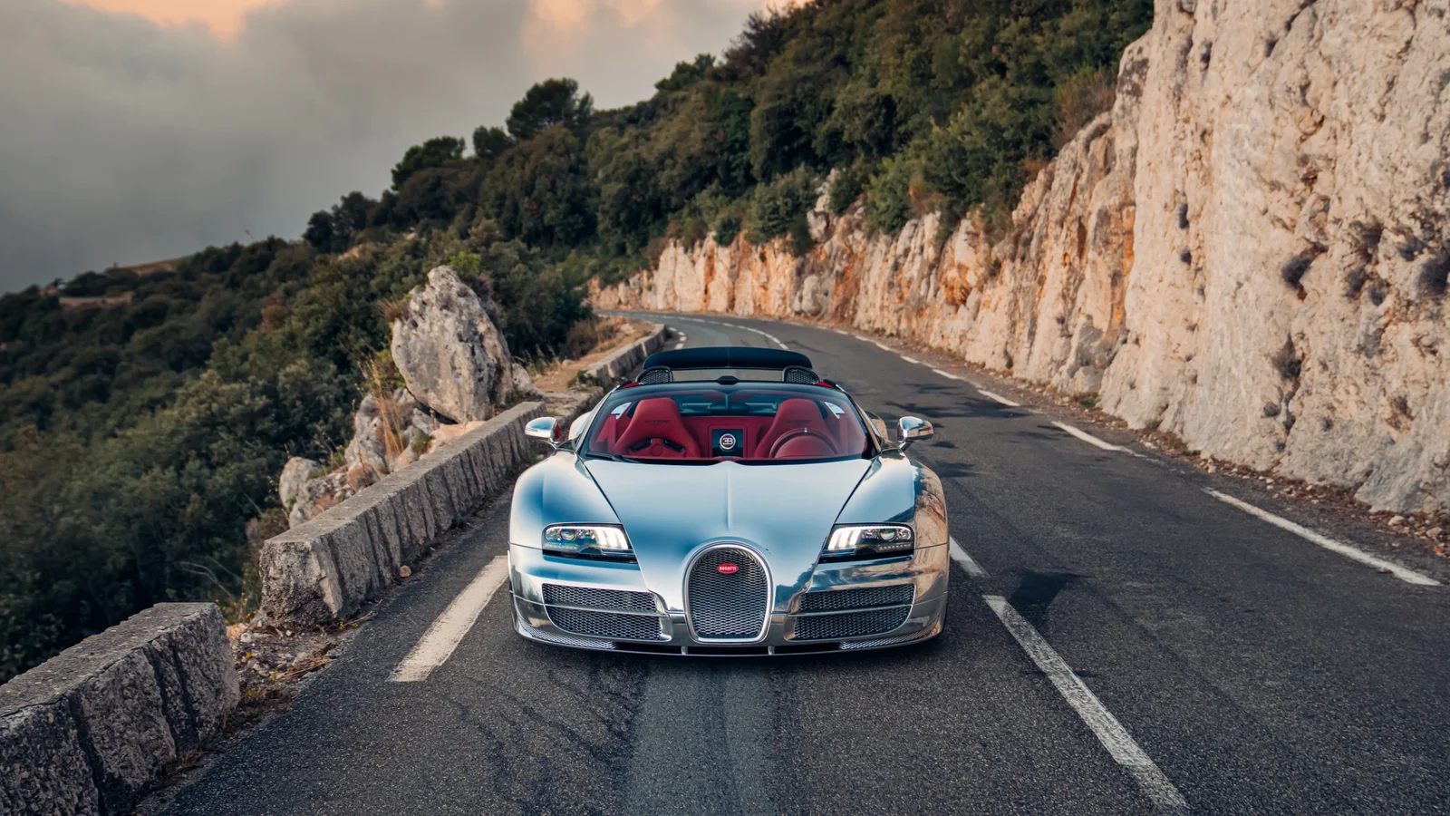 Bugatti Veyron Grand Sport Vitesse cromat, fotografiat frontal pe un drum montan.