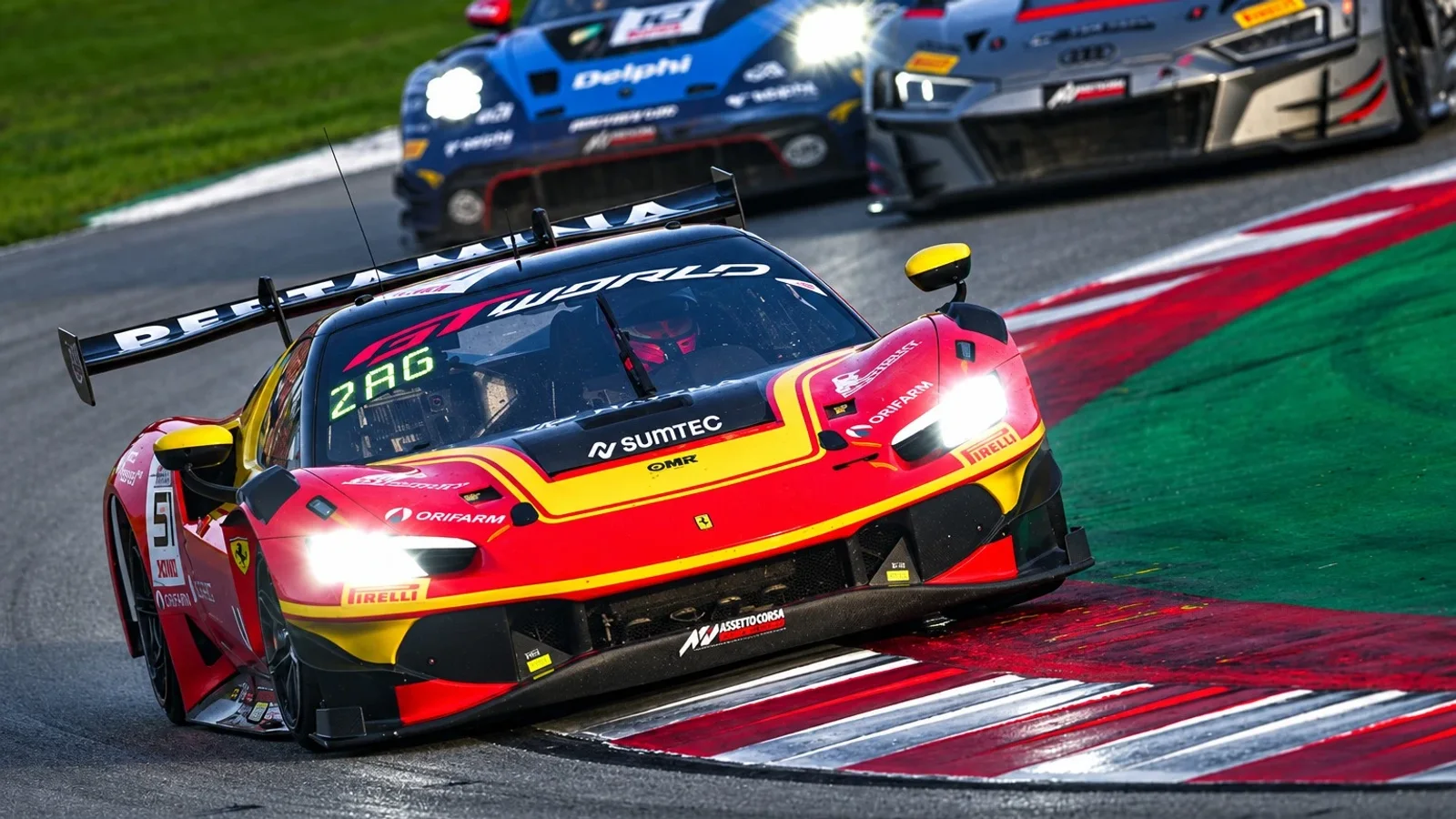 Ferrari 296 GT3 roșu și galben, pilotat pe un viraj de circuit ud, urmat de alte două mașini de competiție.