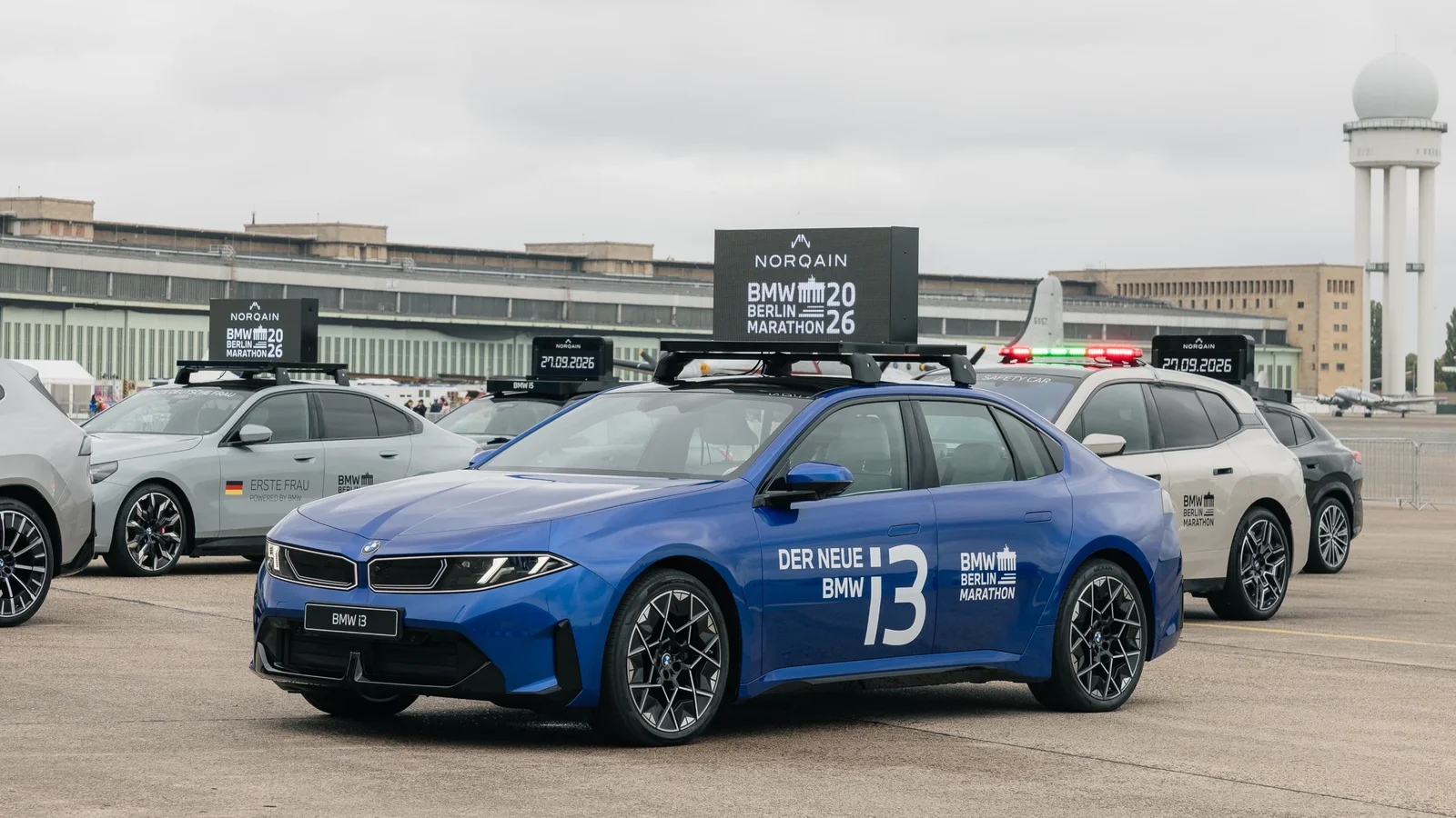 BMW i3 electric albastru, echipat ca automobil oficial pentru BMW BERLIN-MARATHON 2026, alături de alte vehicule ale organizatorilor