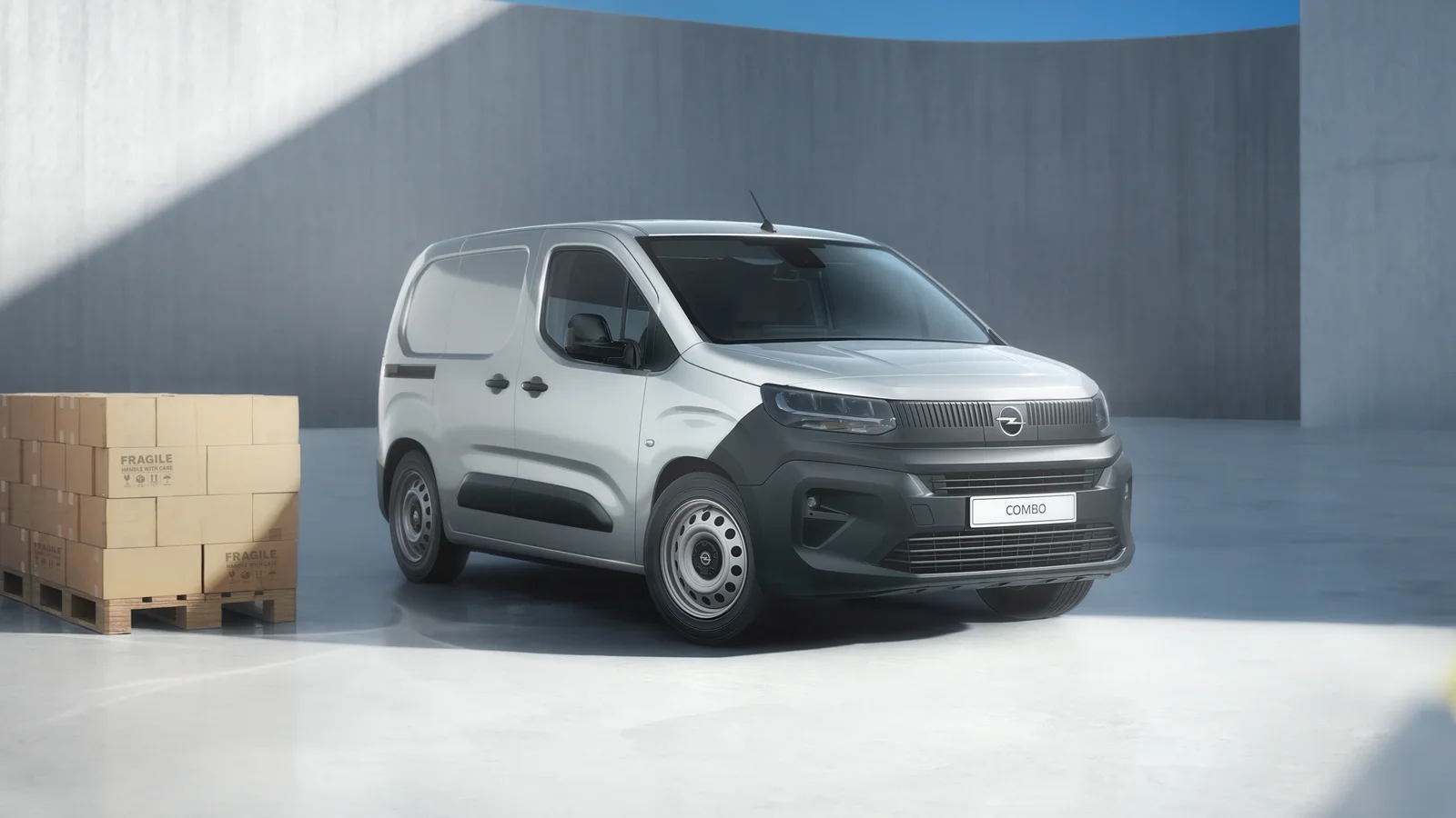 Opel Combo Start alb, fotografiat într-un spațiu industrial, lângă un palet cu cutii din carton.
