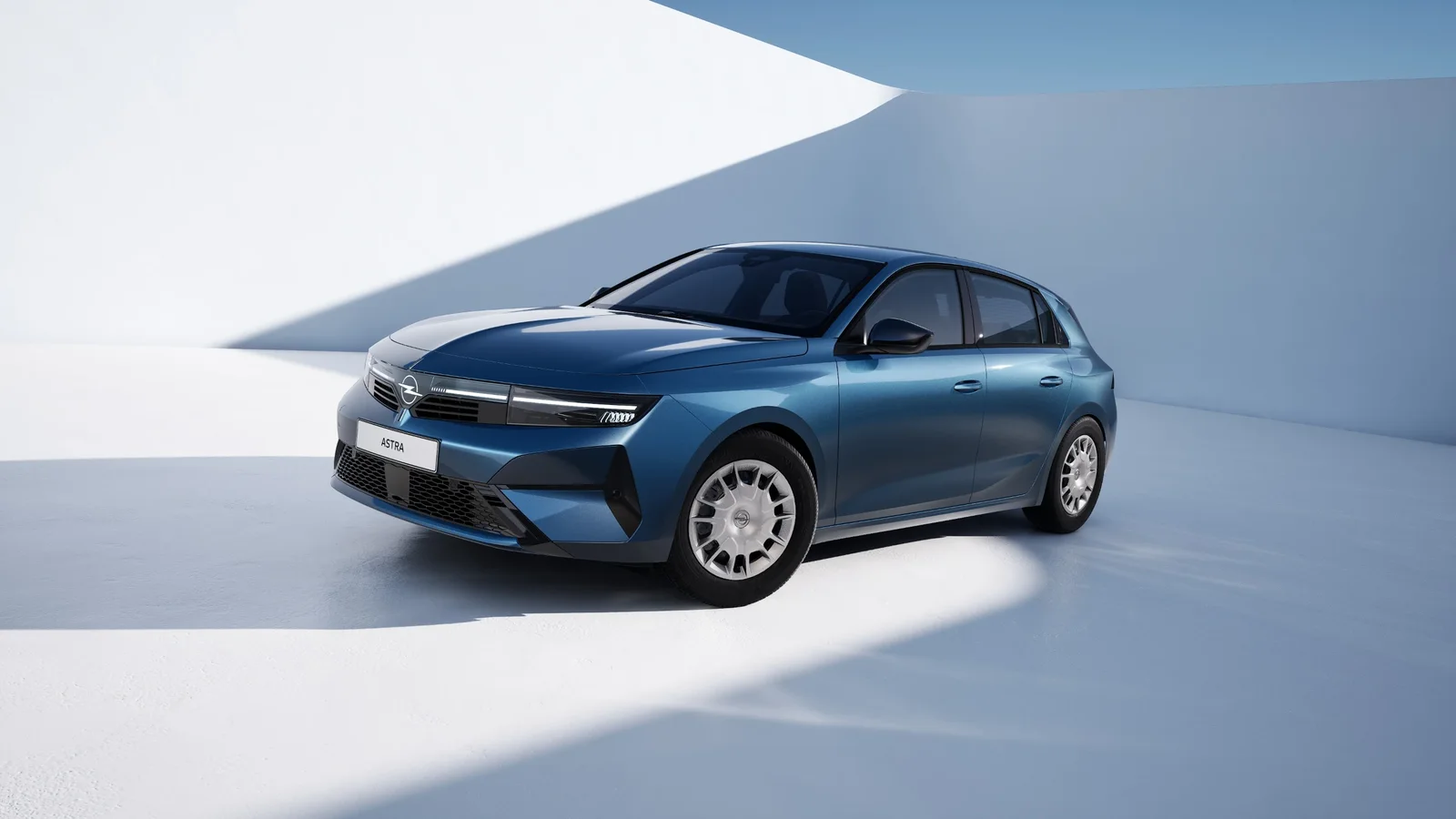 Opel Astra albastru, văzut din față și lateral, într-un decor minimalist iluminat.
