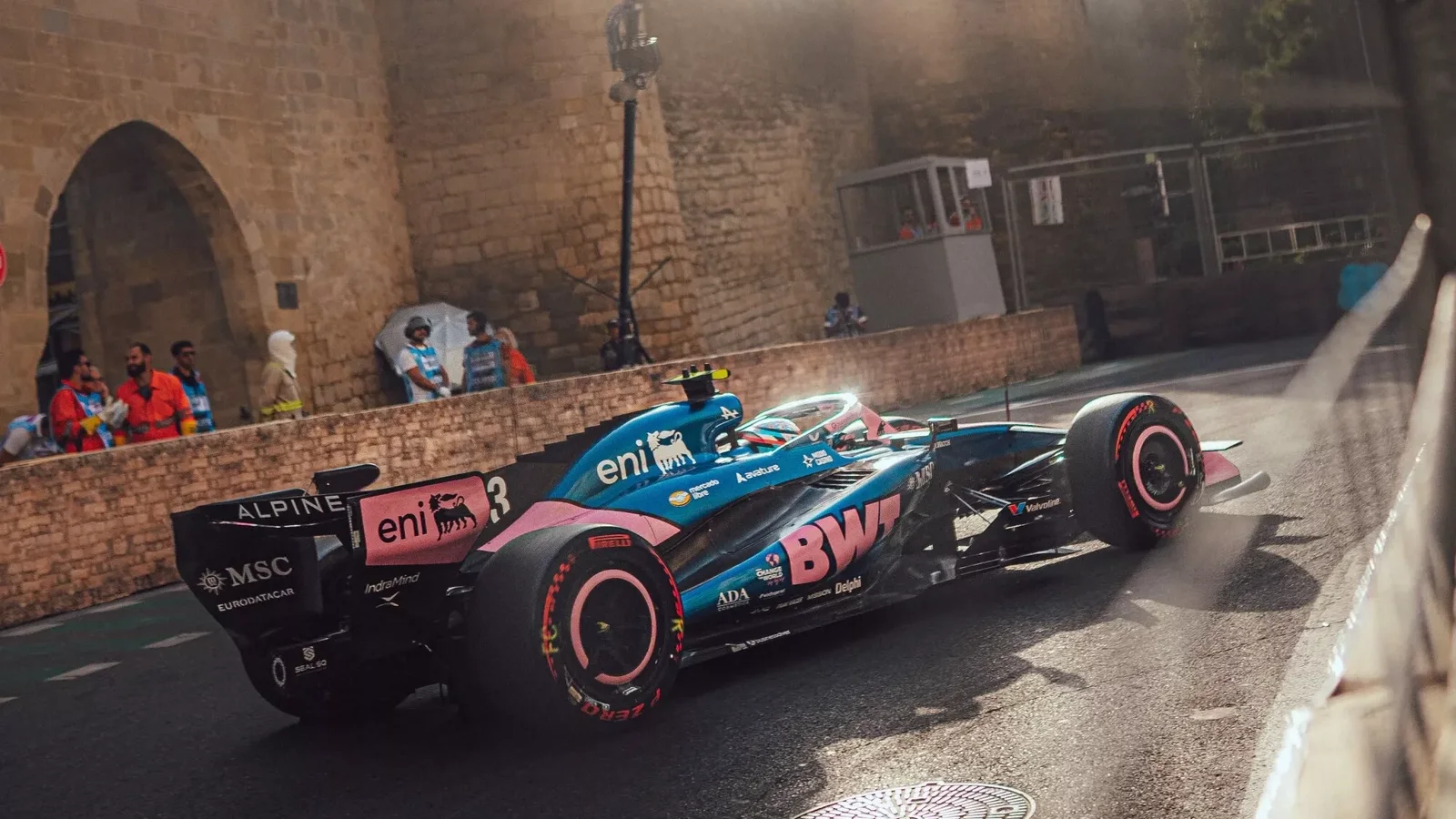 Monopost Alpine de Formula 1 în culorile BWT, fotografiat pe circuitul stradal din Baku, lângă zidurile vechi ale orașului