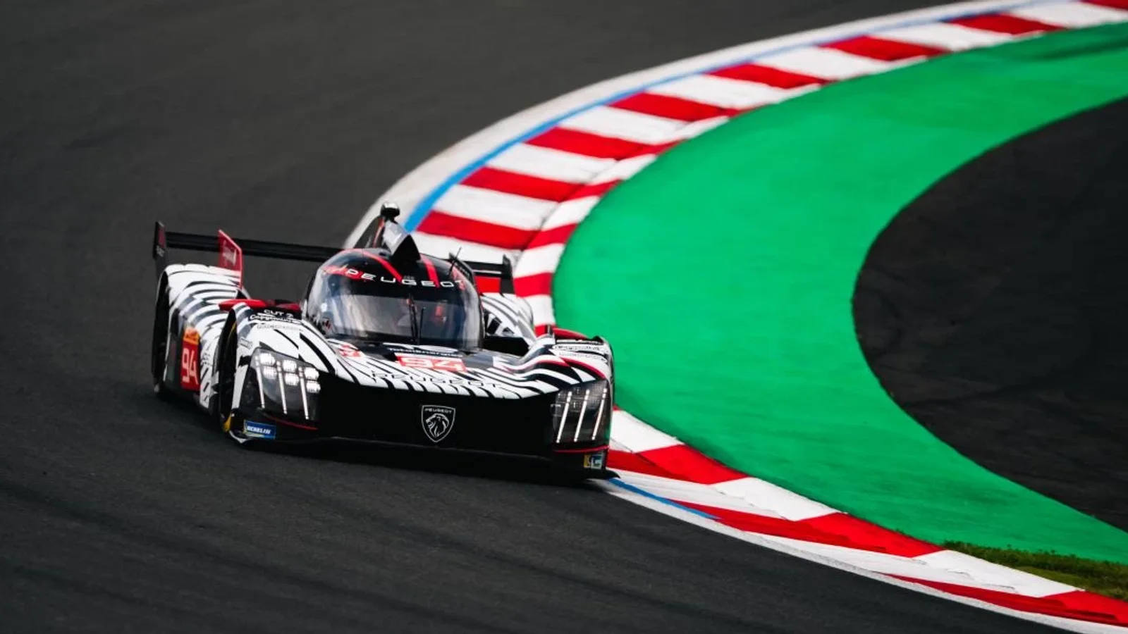 Prototip Peugeot de anduranță, în culori alb-negru, parcurgând un viraj pe circuit.