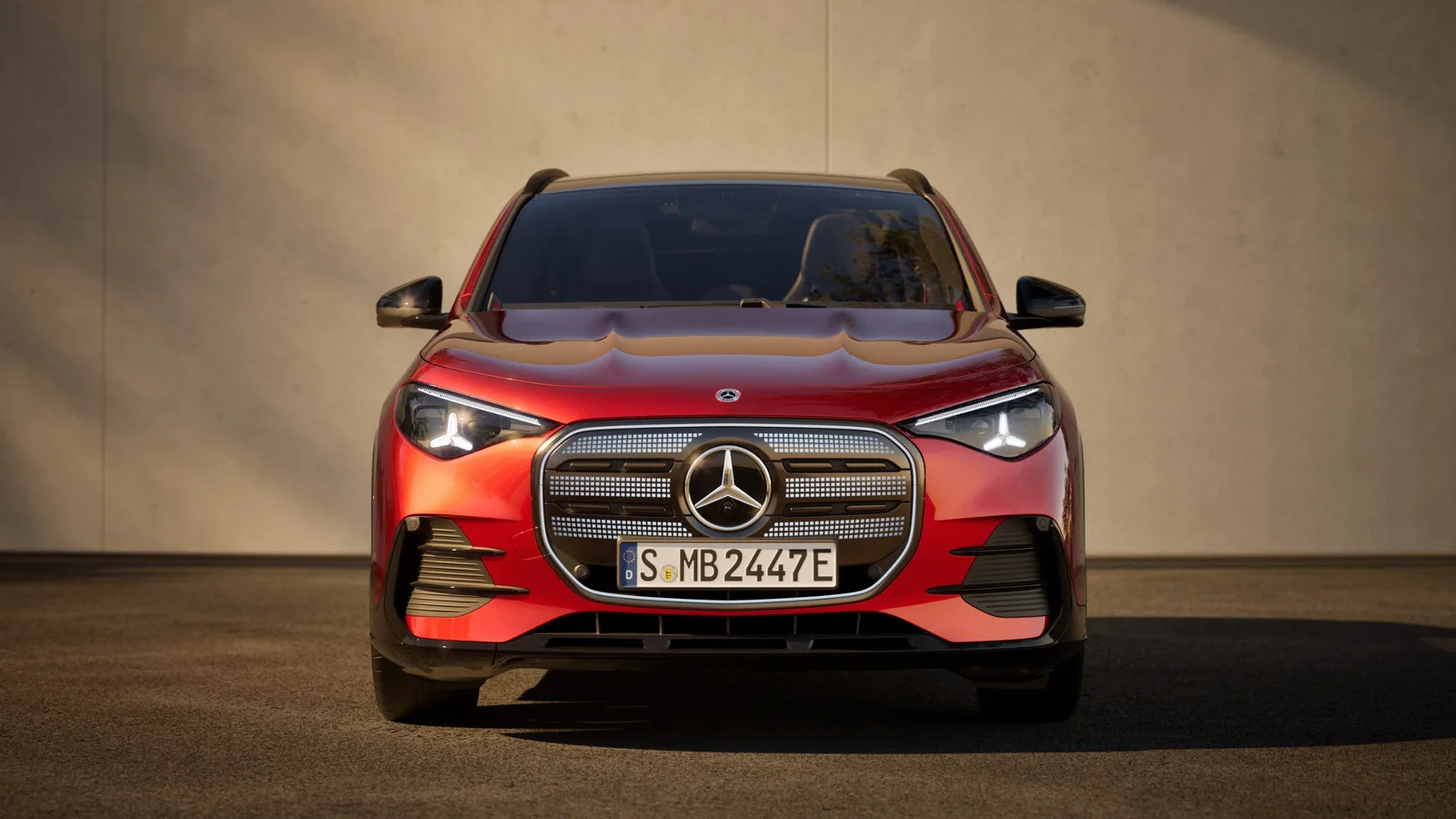 Mercedes-Benz GLA electric roșu, fotografiat din față, cu grila iluminată și farurile aprinse.