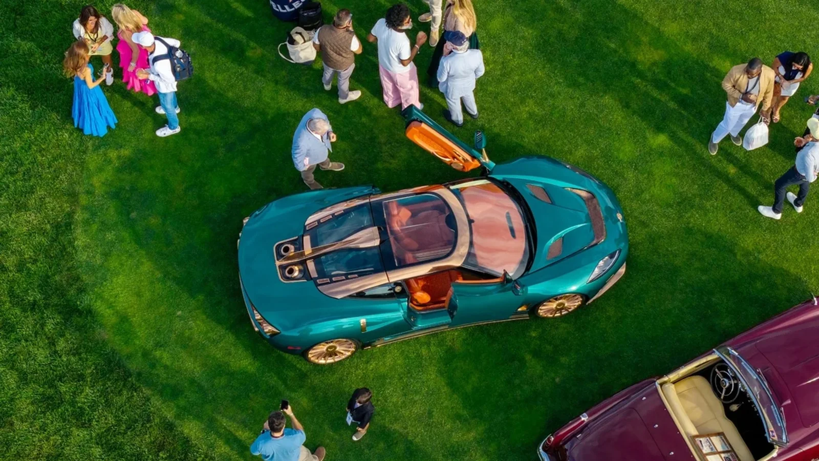 Vedere de sus a unui Spyker verde-turcoaz expus pe gazon, înconjurat de vizitatori.