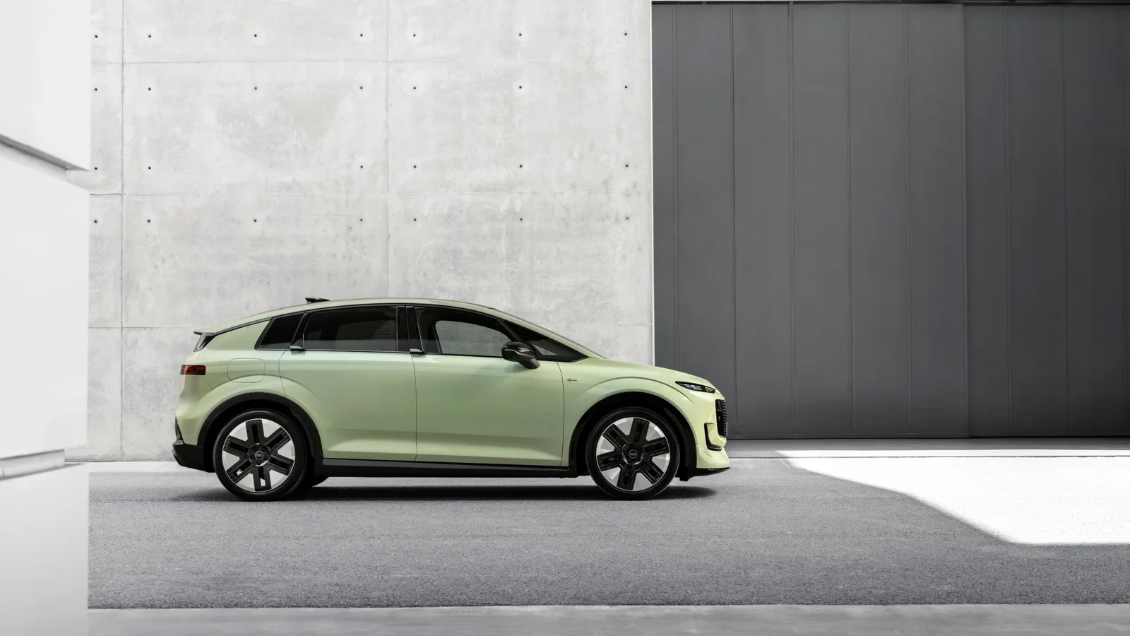 Edit      Audi A2 e-tron verde deschis, văzut din lateral, cu plafon negru și jante bicolore, parcat în fața unei clădiri moderne.