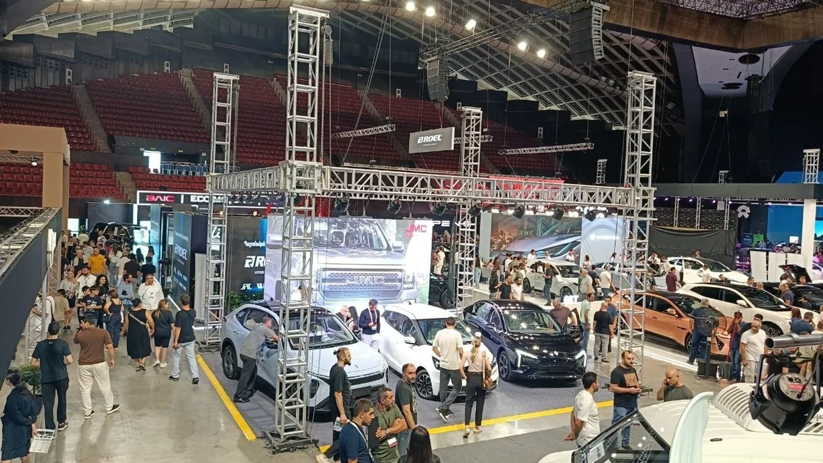 Vedere de ansamblu asupra unui salon auto, cu standuri ale mai multor mărci și vizitatori.
