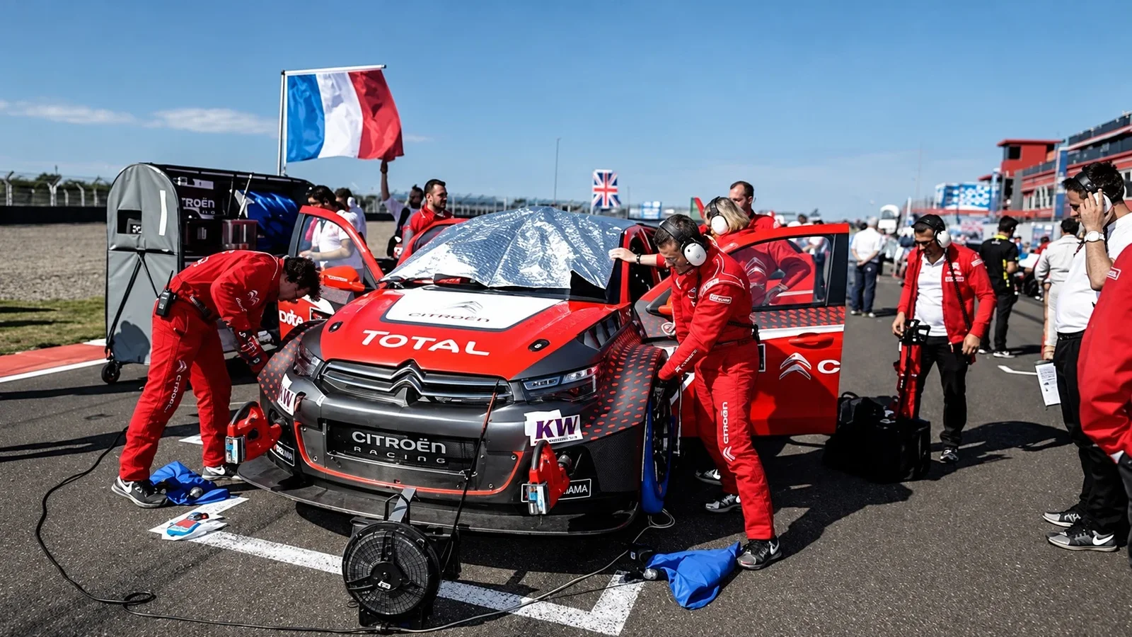 Echipă Citroën Racing pregătind un monopost electric în pit lane, sub drapelul Franței.