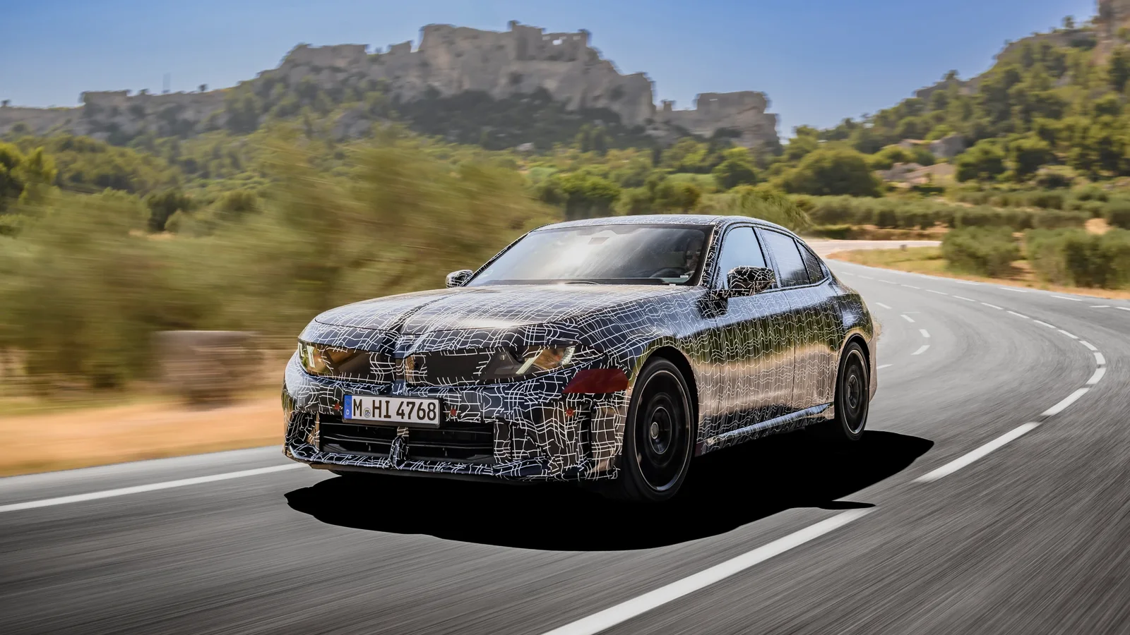 Prototip de sedan BMW Seria 3 acoperit cu folie de camuflaj, surprins din față și lateral în viraj pe un drum din Miramars.