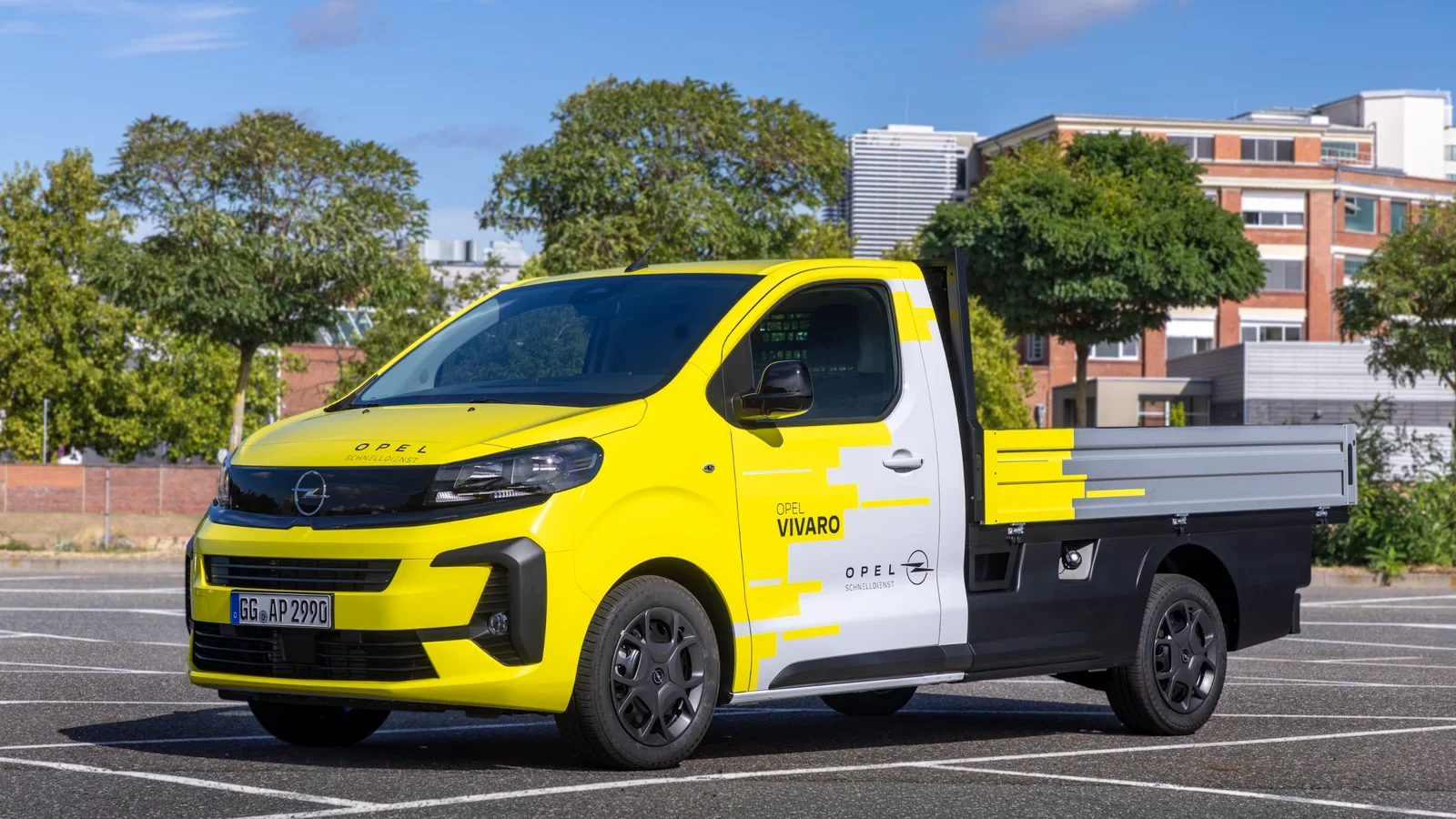 Opel Vivaro Flatbed galben și gri, fotografiat din perspectivă frontal-laterală într-o parcare.
