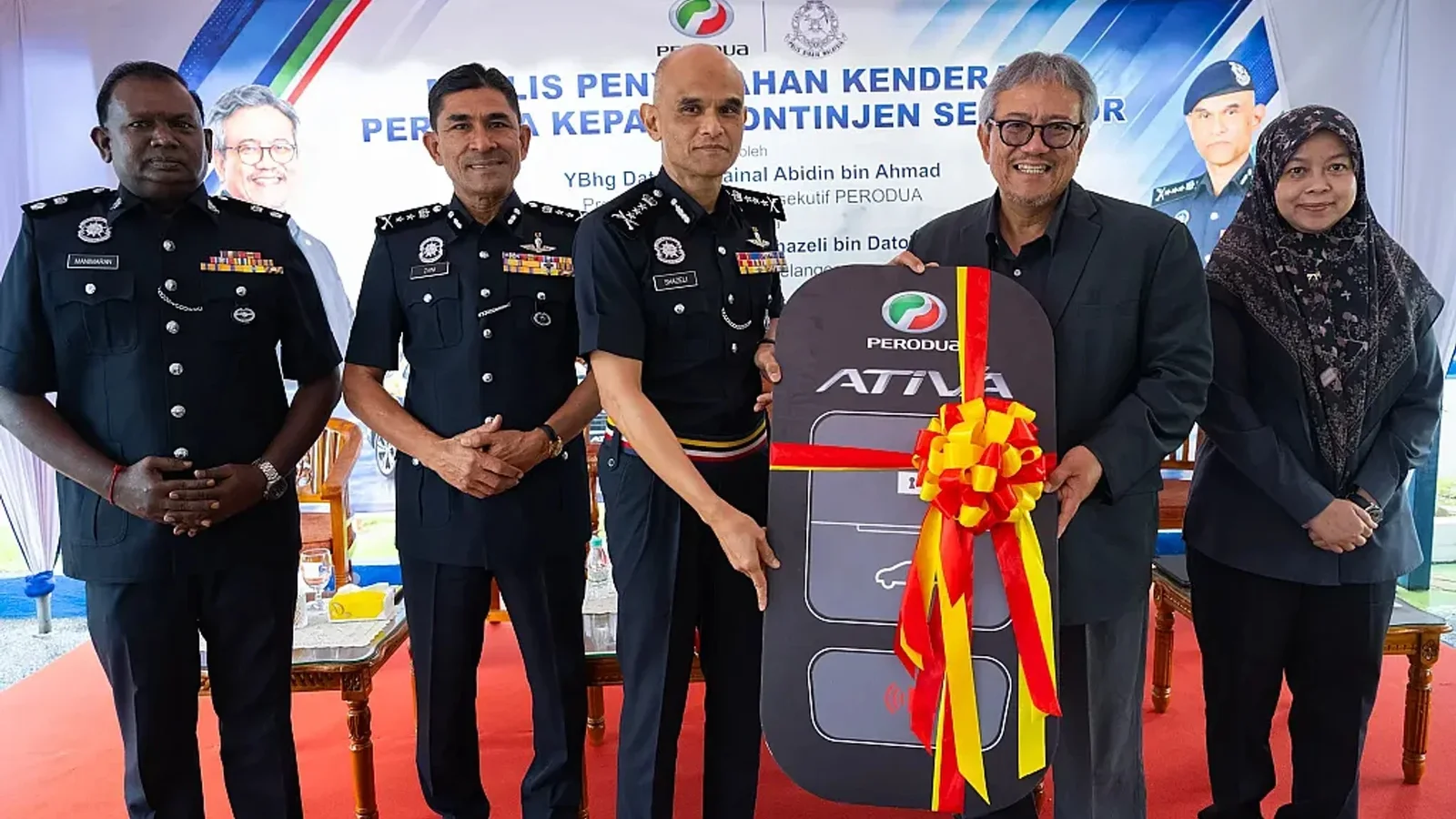 Reprezentanți Perodua și polițiști malaezieni prezintă un card de acces decorat cu panglică, în cadrul unei ceremonii oficiale.