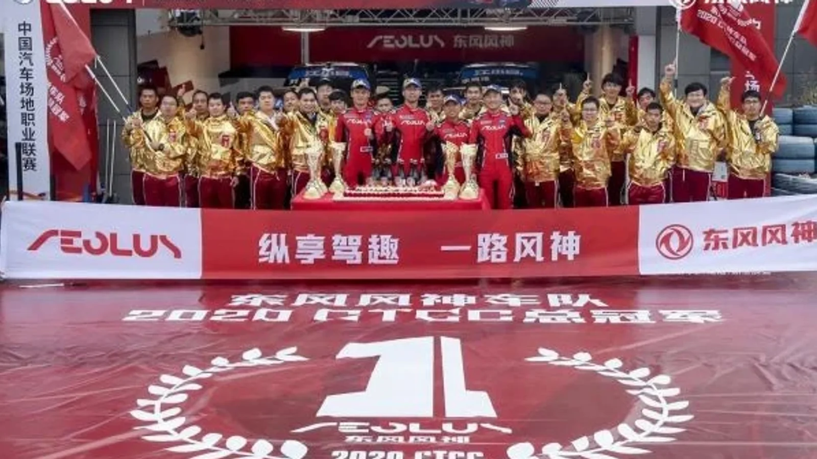 Echipa Dongfeng Aeolus în tricouri aurii și roșii, într-un cadru festiv pe podium, sărbătorind câștigarea CTCC China Cup 2020. În față este logo-ul Aeolus și textul mare „1” cu coroane de lauri pe o platformă roșie. Fundal cu bannere Aeolus.