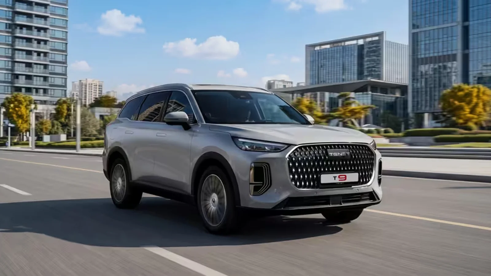 SUV Tenet T9 argintiu, în mers pe un bulevard modern, printre clădiri de birouri.