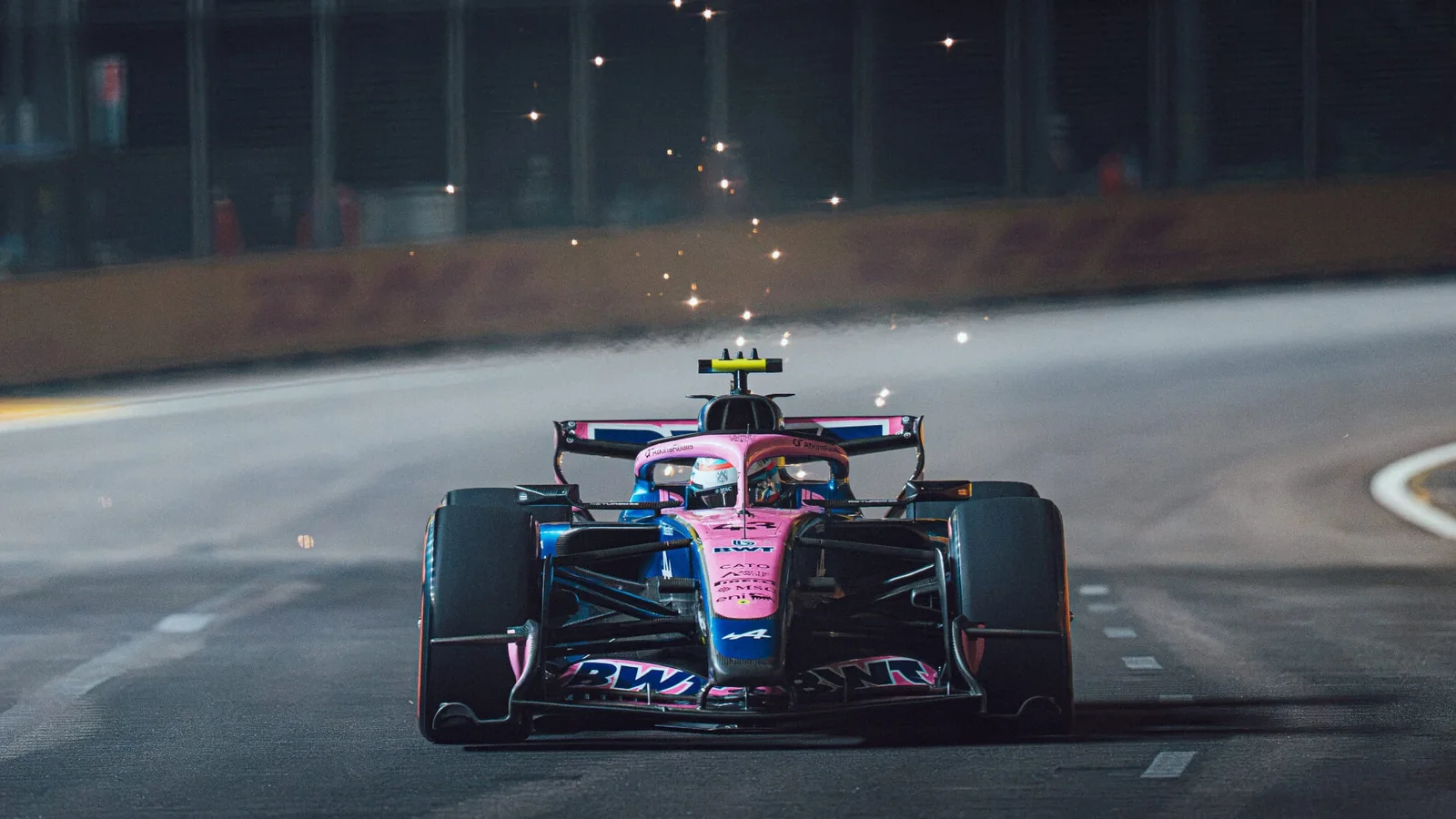 Monopost Alpine de Formula 1, cu livrea roz BWT, rulând noaptea pe circuitul stradal din Singapore.