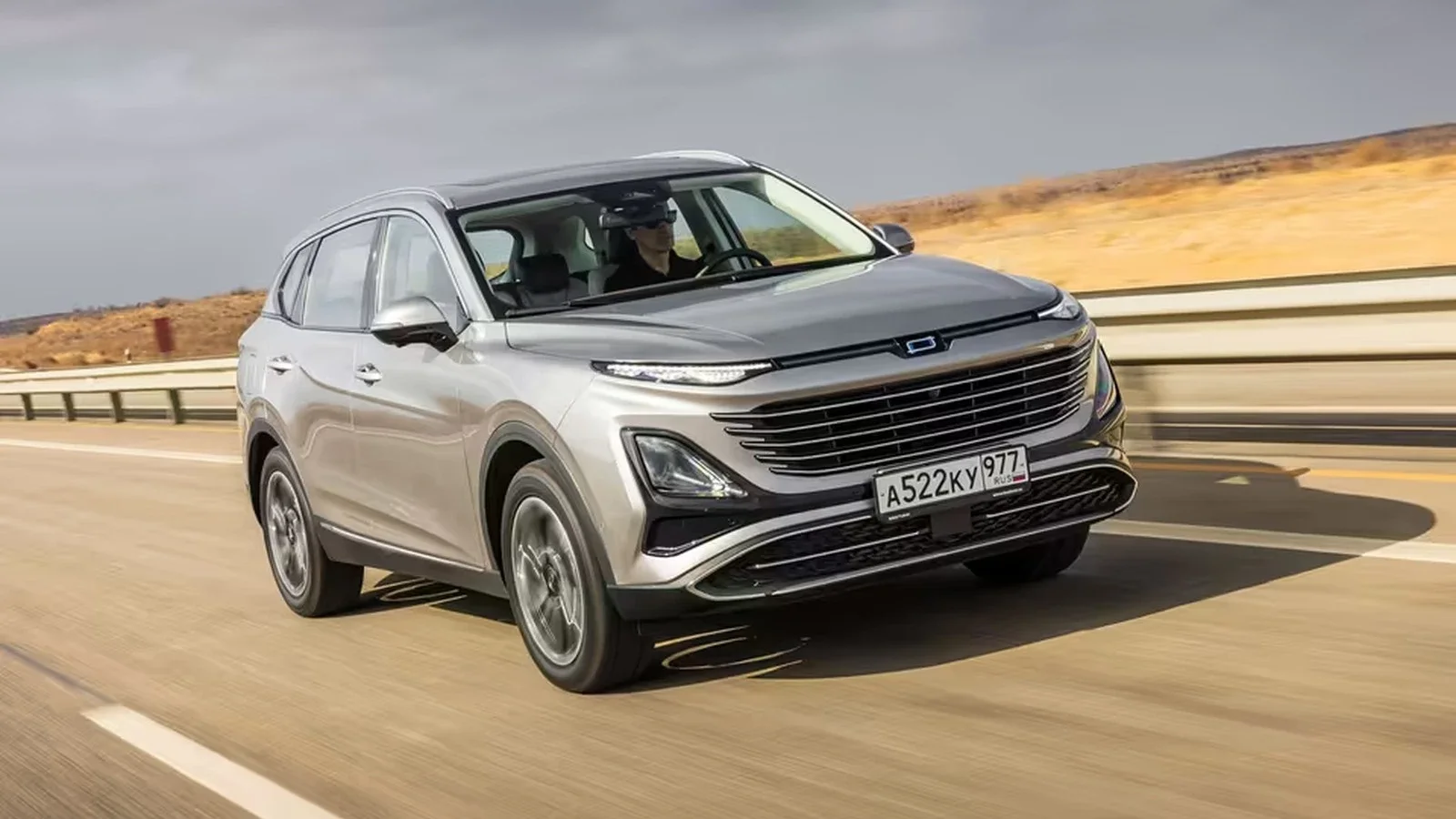 SUV Bestune T90 argintiu, fotografiat în mers pe un drum de șosea, cu peisaj arid în fundal